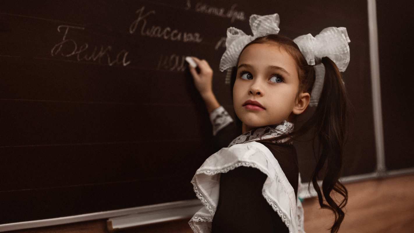 Открытка девочка в школе пишет на доске мелом  1 сентября  From September 1 