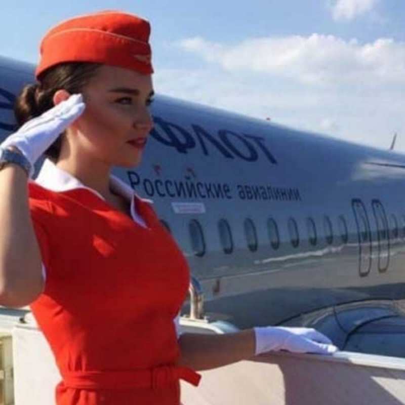 Открытка стюардесса в красном отдает честь чудесного полета Have a good trip 